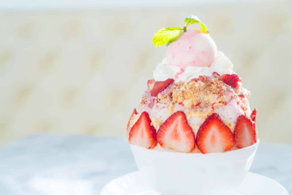 A bowl of homemade strawberry shortcake ice cream, with visible chunks of fresh strawberries and sponge cake pieces.